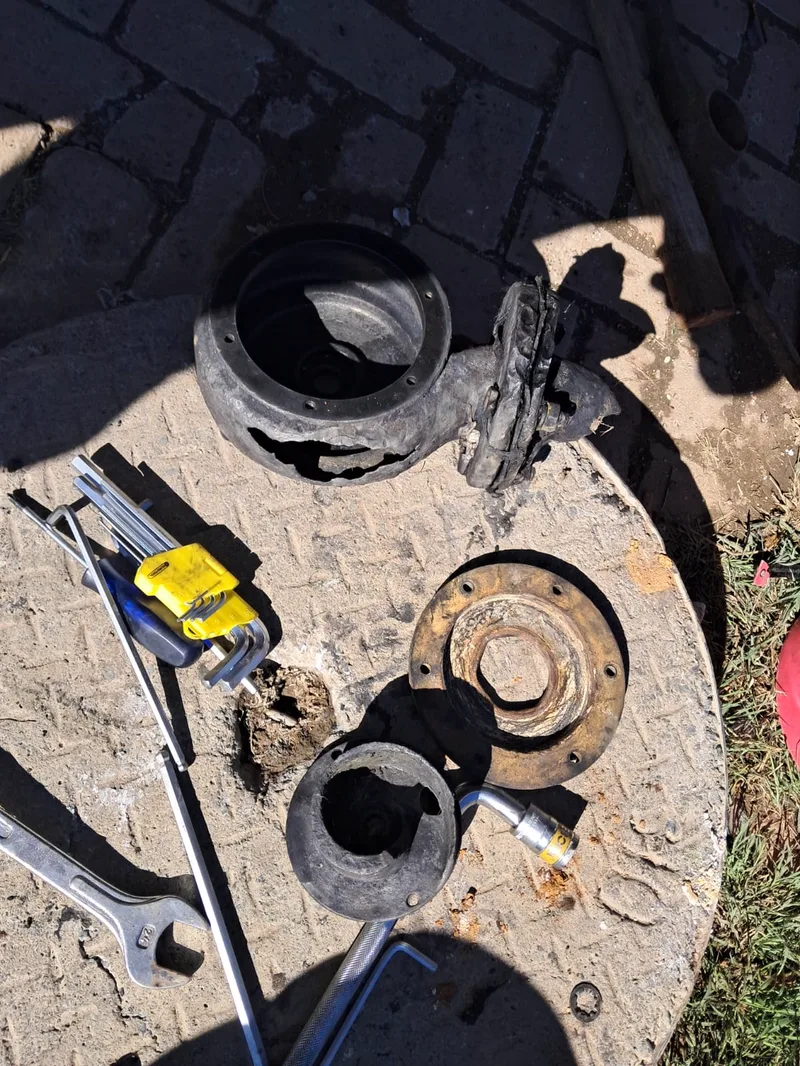 A pump stripped down on site: the housing split open, flange and seal removed, with hex keys and spanners laid out beside the parts